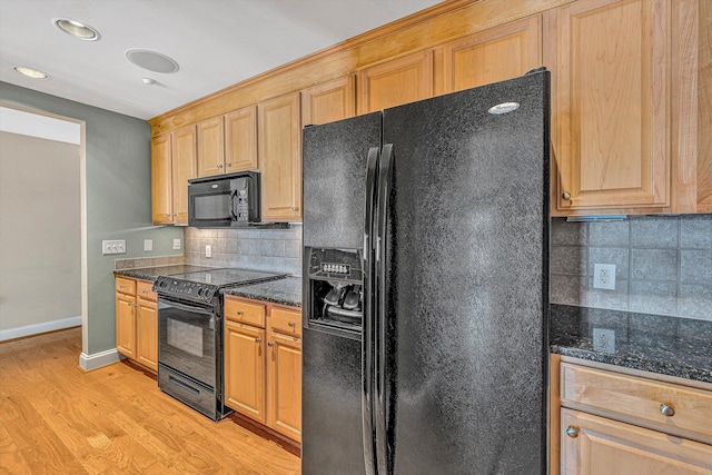 kitchen featuring baseboards, light wood finished floors, black appliances, tasteful backsplash, and dark stone countertops