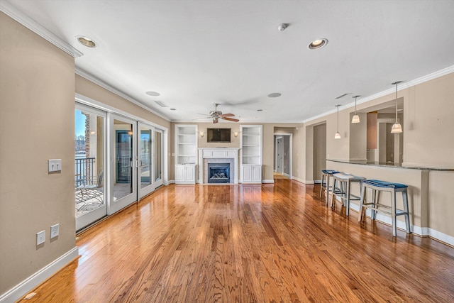 unfurnished living room featuring ornamental molding, a fireplace, baseboards, and wood finished floors