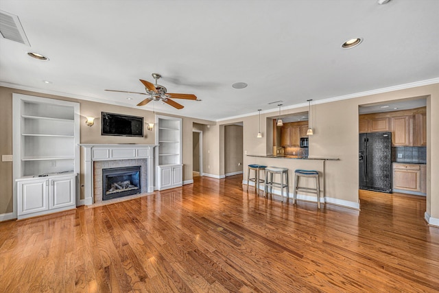 unfurnished living room featuring visible vents, ornamental molding, wood finished floors, and a tile fireplace