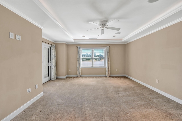 spare room featuring crown molding, a raised ceiling, light colored carpet, and baseboards