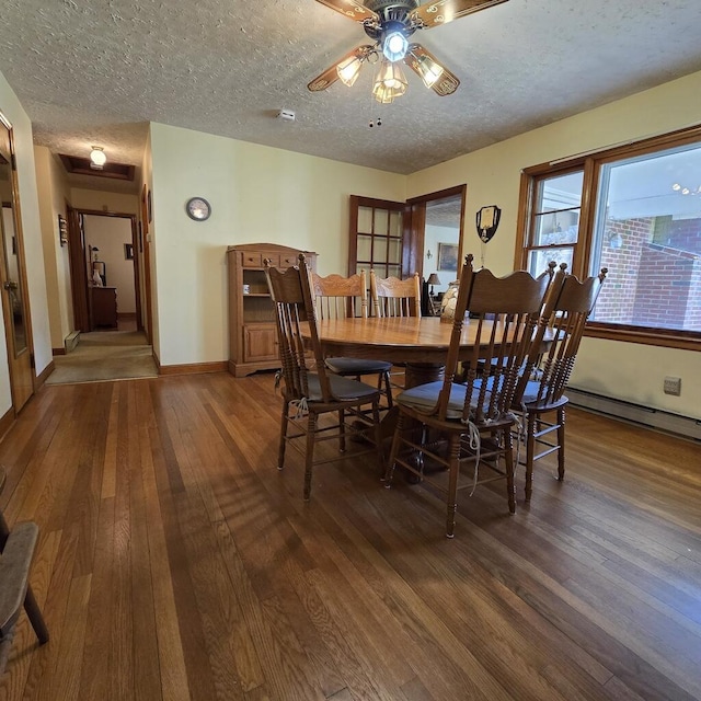 dining space with dark wood finished floors, a baseboard radiator, ceiling fan, a textured ceiling, and baseboards