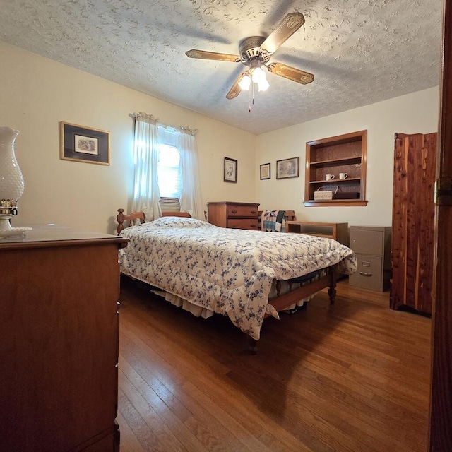 bedroom with a textured ceiling, dark wood-type flooring, and a ceiling fan