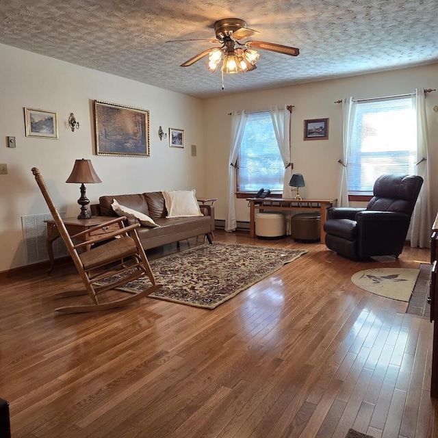 living room featuring a ceiling fan, a wealth of natural light, wood-type flooring, and a textured ceiling