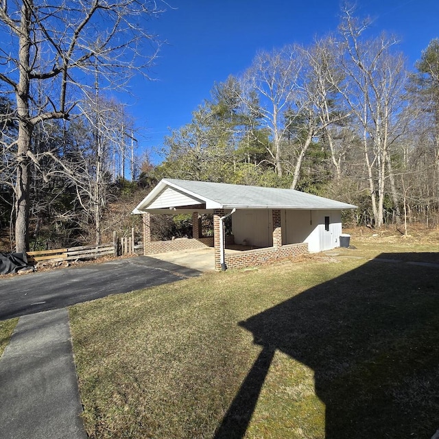 exterior space with aphalt driveway, brick siding, and a lawn