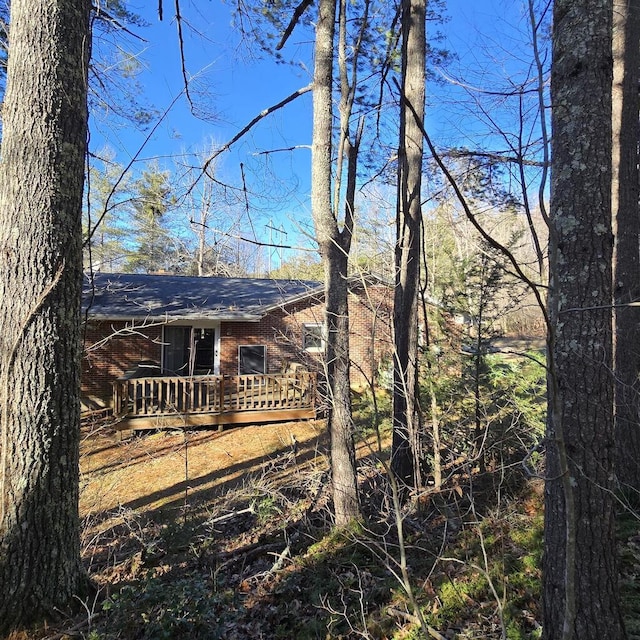 view of side of property featuring brick siding and a deck