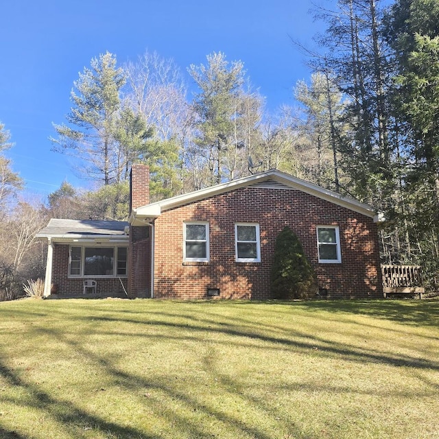 view of property exterior with crawl space, brick siding, a lawn, and a chimney