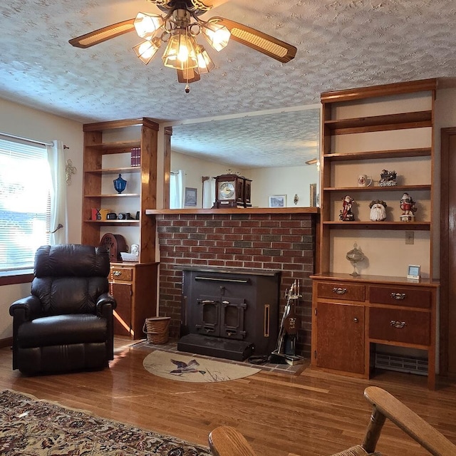 living room with a ceiling fan, a textured ceiling, and wood finished floors