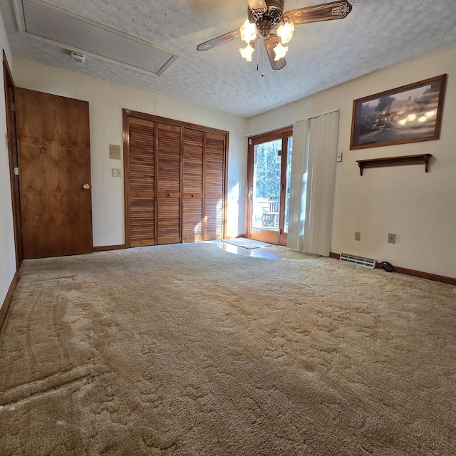 unfurnished bedroom featuring a closet, visible vents, attic access, carpet flooring, and a textured ceiling