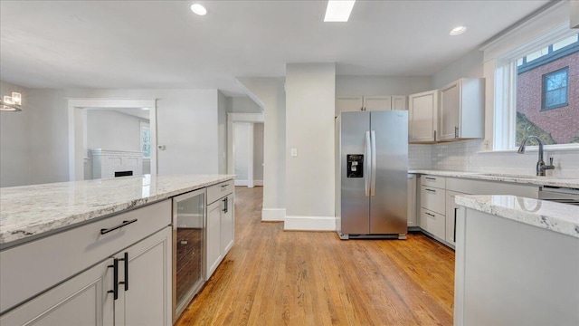 kitchen with wine cooler, a sink, white cabinetry, and stainless steel fridge with ice dispenser