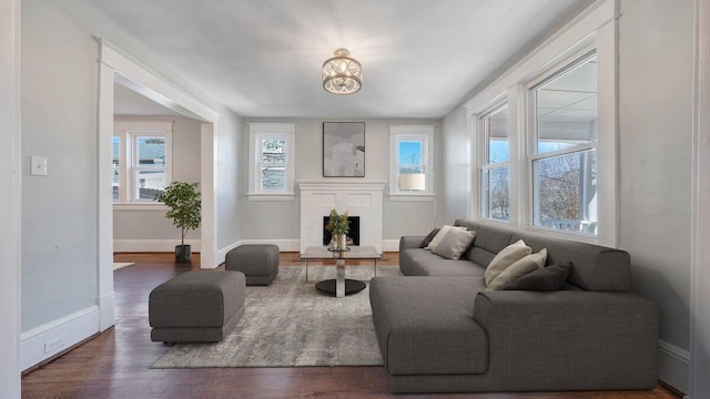 sitting room with a fireplace, baseboards, and dark wood-style flooring