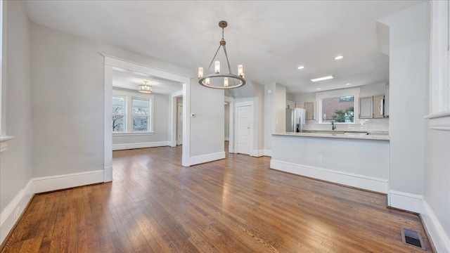 kitchen featuring a peninsula, visible vents, light countertops, decorative backsplash, and dark wood finished floors