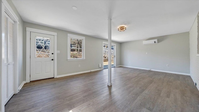 entryway with an AC wall unit, baseboards, and wood finished floors