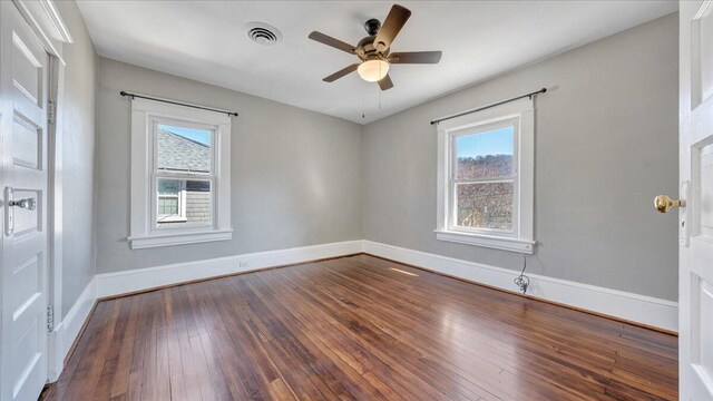 empty room featuring dark wood-style flooring, visible vents, ceiling fan, and baseboards