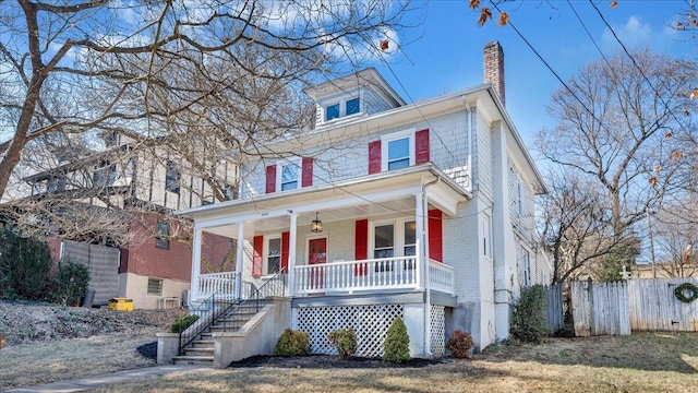 traditional style home featuring a chimney, fence, a porch, and brick siding