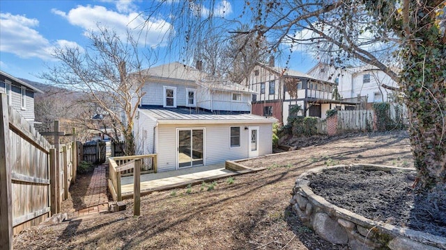 back of house with a standing seam roof, a fenced backyard, a residential view, and metal roof