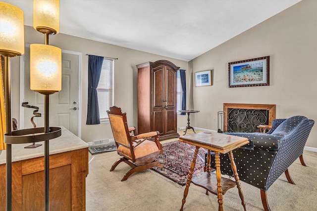 living area with visible vents, lofted ceiling, a fireplace, baseboards, and light colored carpet