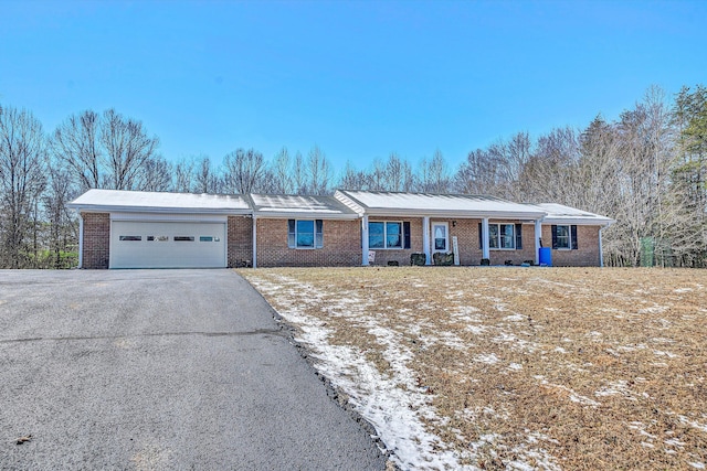 ranch-style house featuring driveway, an attached garage, and brick siding