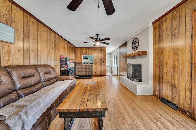 5359 Booker T Washington Hwy, Rocky Mount, VA 24151 - living room featuring a ceiling fan, light wood-style floors, wood walls, a fireplace, and crown molding