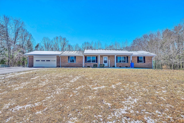 ranch-style house featuring a front lawn, brick siding, driveway, and an attached garage