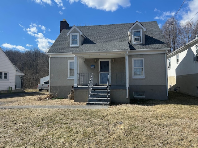 view of front facade featuring covered porch, a chimney, a front lawn, and roof with shingles