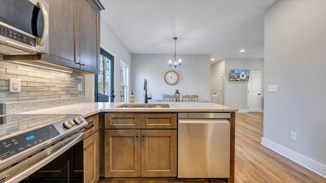 kitchen with tasteful backsplash, light countertops, appliances with stainless steel finishes, a sink, and baseboards