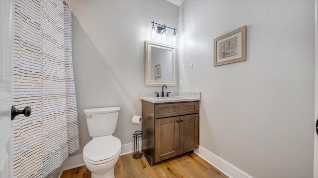 bathroom featuring baseboards, vanity, toilet, and wood finished floors