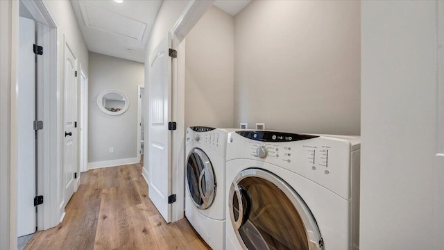 laundry area with laundry area, attic access, baseboards, light wood-style floors, and washing machine and dryer