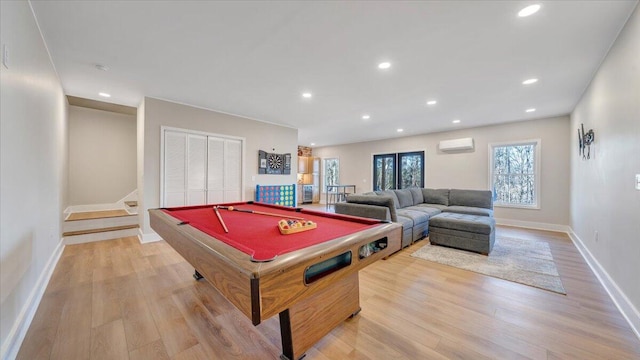 recreation room featuring recessed lighting, an AC wall unit, baseboards, and light wood finished floors