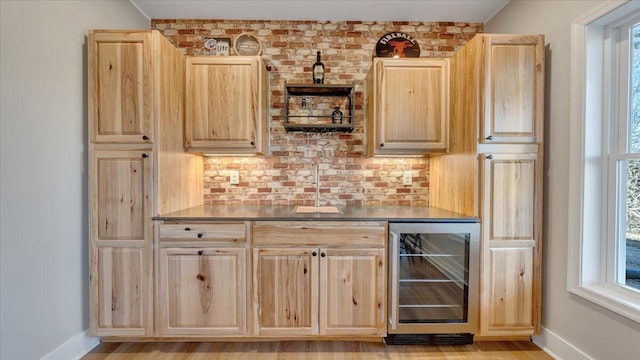 bar featuring wine cooler, plenty of natural light, a sink, and baseboards