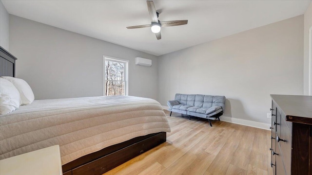 bedroom featuring ceiling fan, an AC wall unit, light wood-style flooring, and baseboards