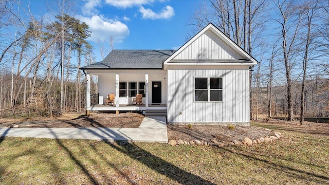 modern farmhouse with a front lawn, a porch, and roof with shingles