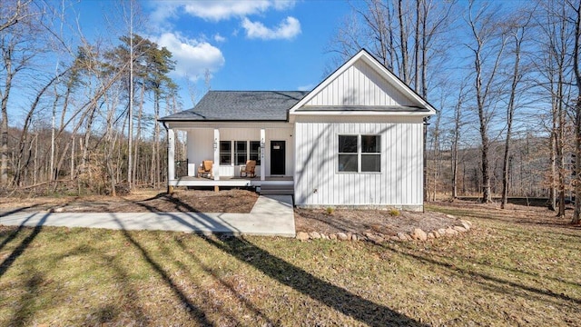 view of front of home featuring roof with shingles, a porch, board and batten siding, and a front yard