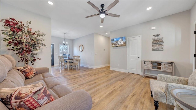 living room featuring light wood-style floors, recessed lighting, baseboards, and ceiling fan with notable chandelier