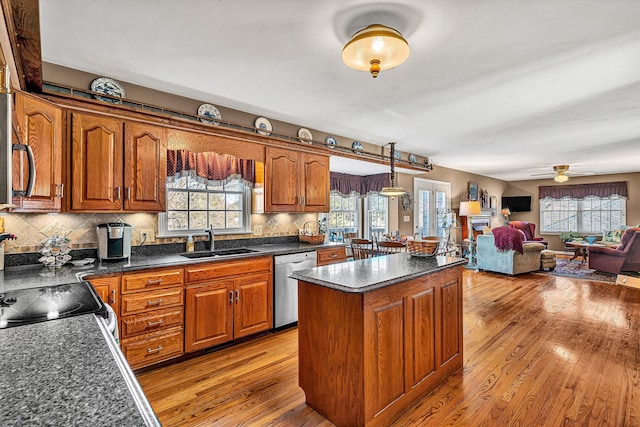 kitchen featuring stainless steel dishwasher, brown cabinetry, and a sink