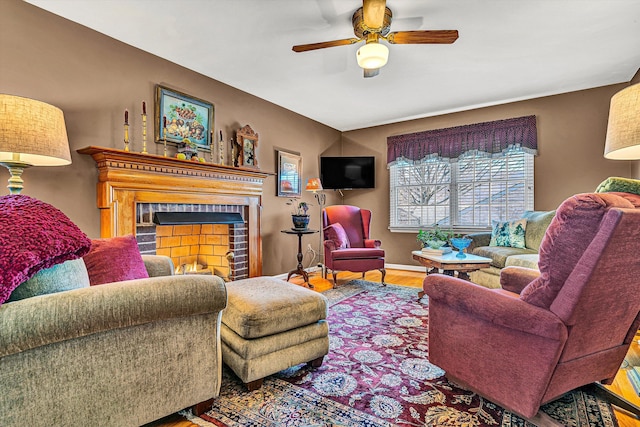 living room featuring ceiling fan, a tile fireplace, wood finished floors, and baseboards