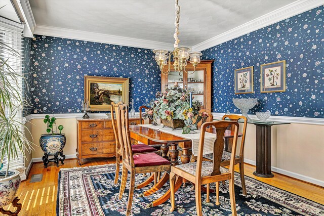 dining area with wallpapered walls, baseboards, a notable chandelier, and wood finished floors