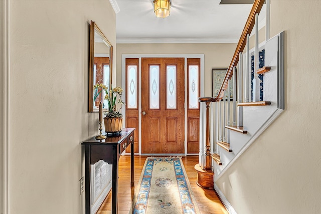 foyer featuring stairway, wood finished floors, and crown molding