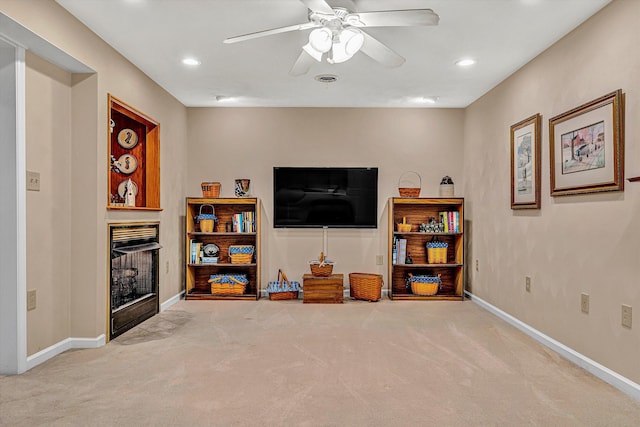 living room featuring carpet, a fireplace with flush hearth, baseboards, and ceiling fan