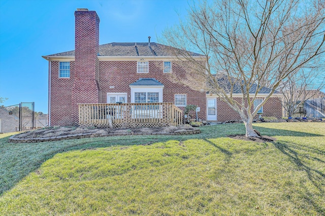 back of house featuring brick siding, a chimney, a lawn, fence, and a wooden deck