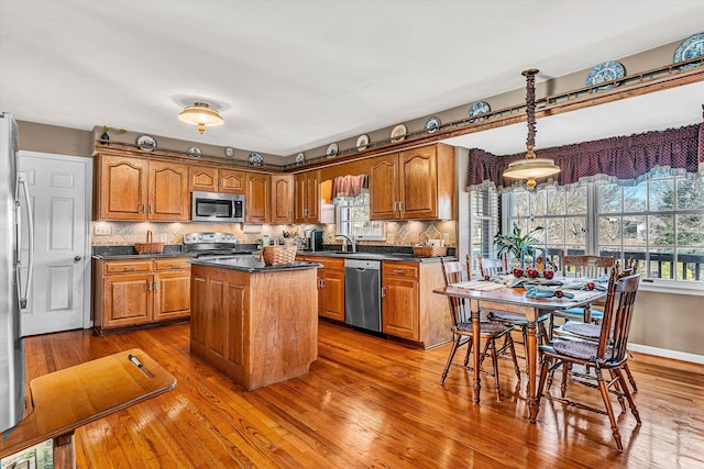 kitchen featuring hardwood / wood-style flooring, stainless steel appliances, a sink, brown cabinets, and a center island