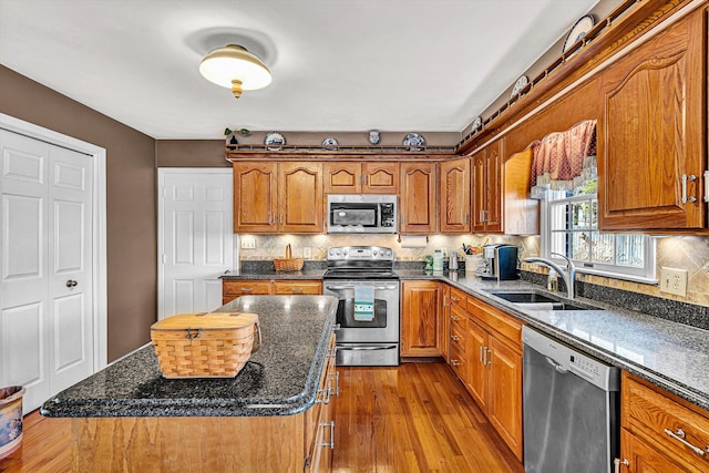 kitchen featuring decorative backsplash, brown cabinetry, appliances with stainless steel finishes, wood finished floors, and a sink