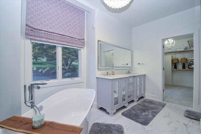 bathroom featuring double vanity, baseboards, marble finish floor, an inviting chandelier, and a freestanding tub