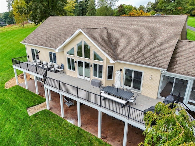 rear view of property featuring a shingled roof, a lawn, and a wooden deck