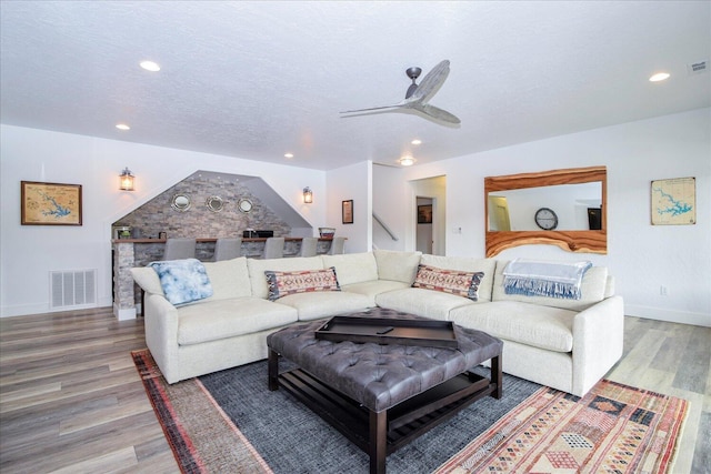 living room featuring a textured ceiling, visible vents, wood finished floors, and recessed lighting