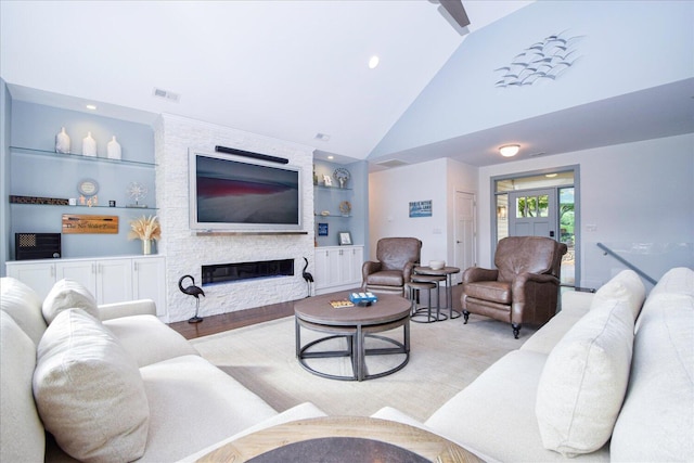 living room featuring high vaulted ceiling, a stone fireplace, visible vents, and built in features