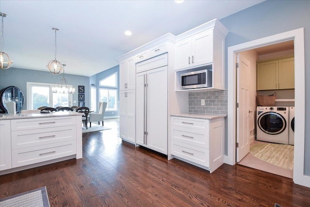 kitchen featuring pendant lighting, dark wood finished floors, washer and clothes dryer, stainless steel microwave, and white cabinets