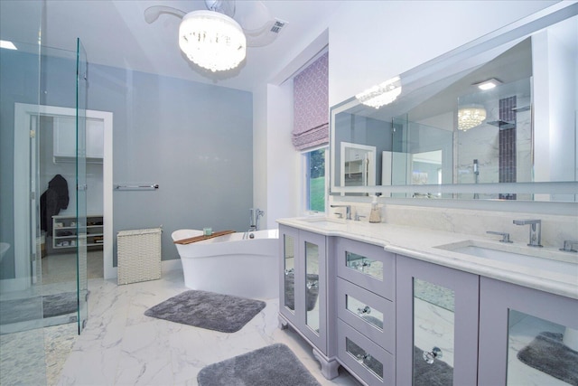 full bath featuring marble finish floor, an inviting chandelier, a sink, and a soaking tub