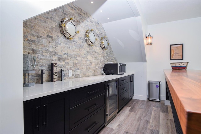 kitchen with light wood-style floors, wine cooler, wood counters, and dark cabinets