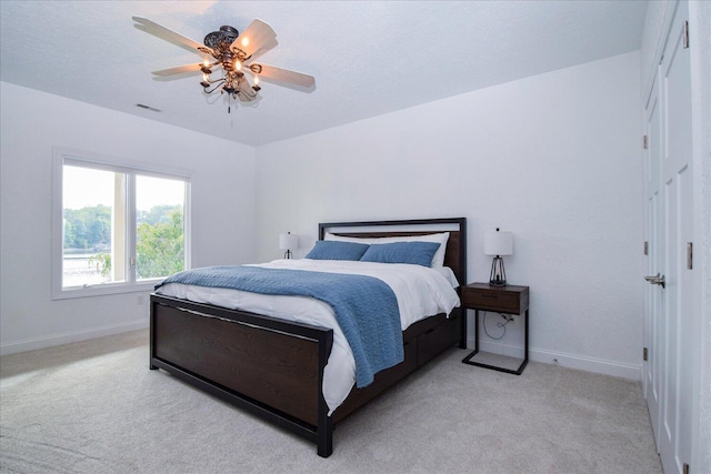 bedroom with baseboards, visible vents, a ceiling fan, and light colored carpet