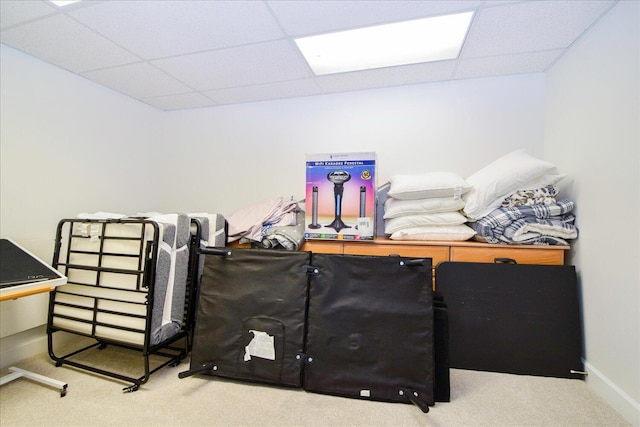 interior space featuring carpet floors, a drop ceiling, and baseboards